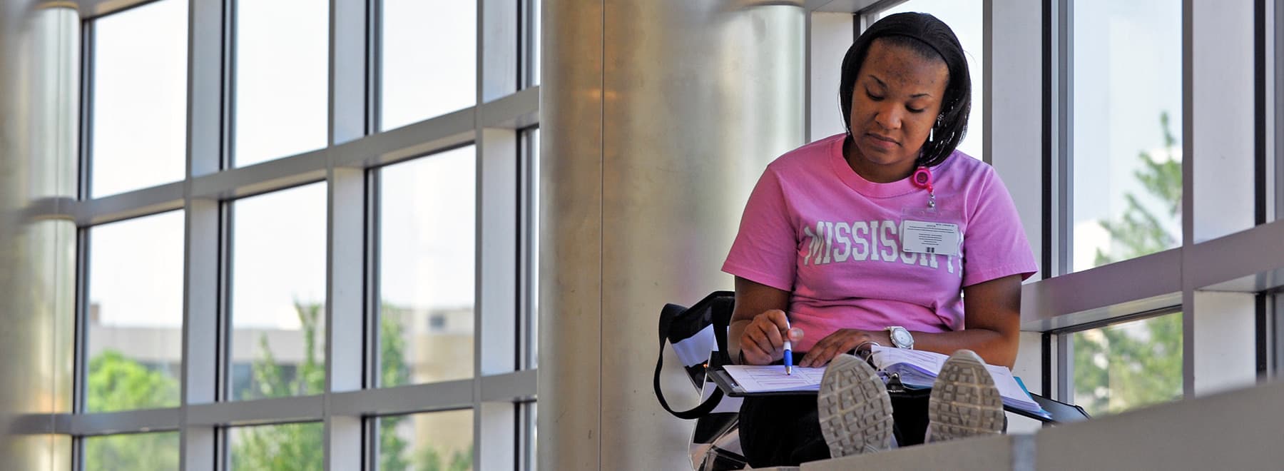 Student reading in front of windows.